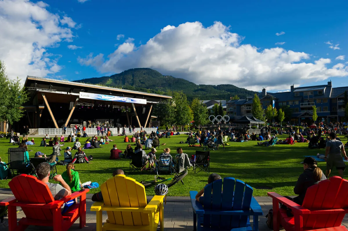 La Whistler Olympic Plaza en verano, con el escenario y los aros olímpicos detrás del césped que en invierno se convierte en la pista de patinaje. — Whistler Olympic Plaza Outdoor Rink