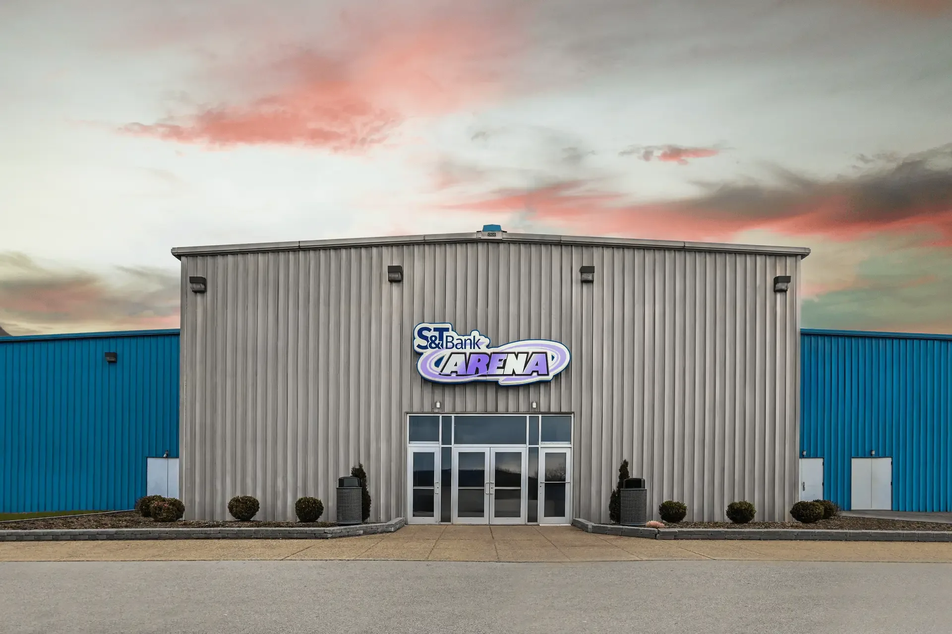 Arena's grey corrugated-metal entrance bay under the S&T Bank Arena sign, flanked by bright blue metal wings — White Township Recreation Complex / S&T Bank Arena