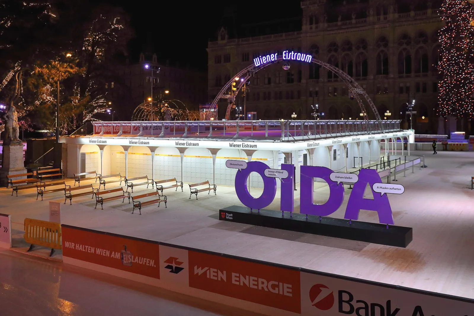 The Wiener Eistraum rink on the Rathausplatz at night, empty ice with the City Hall behind — Wiener Eistraum
