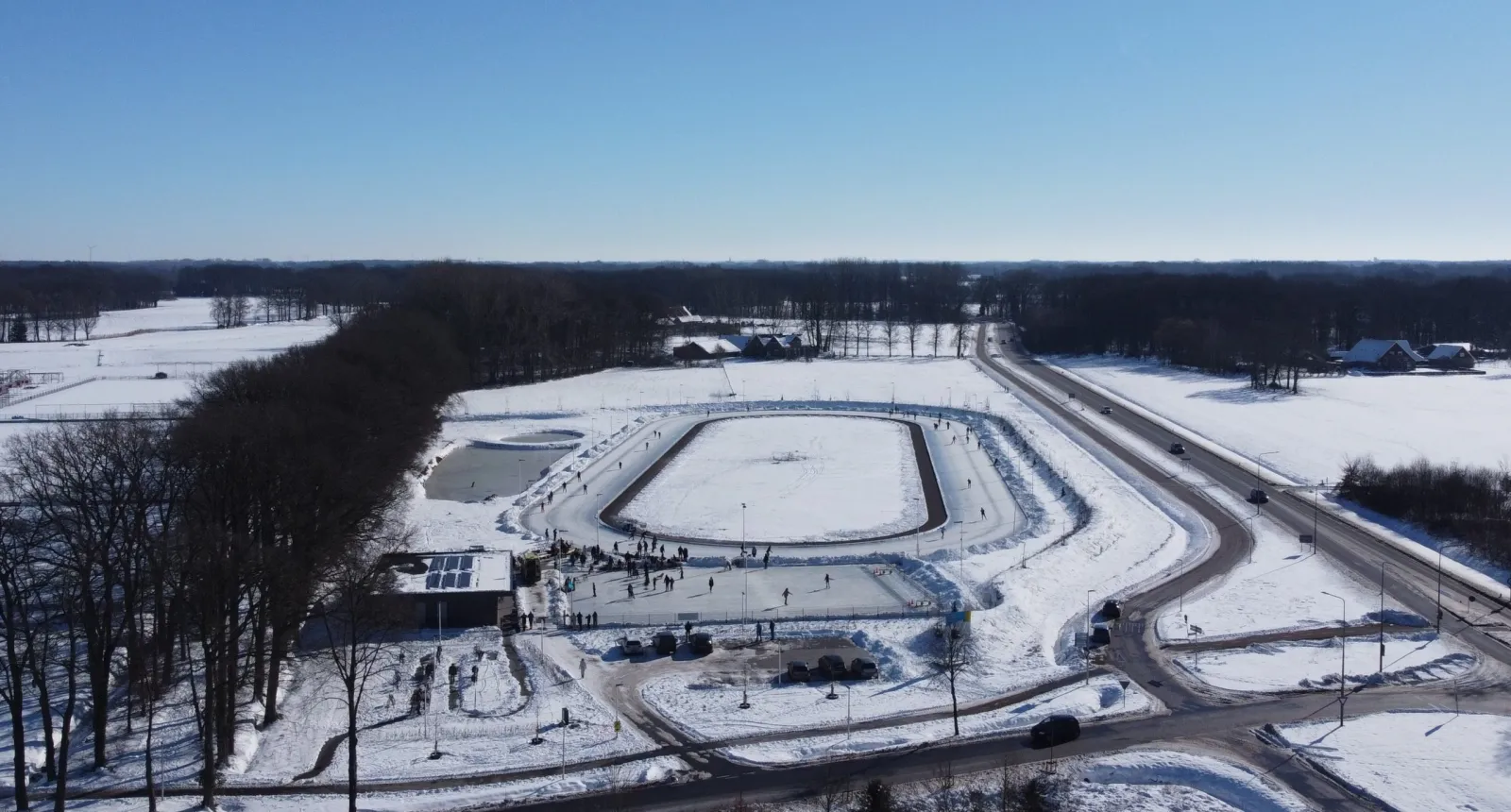 Een dronebeeld van het besneeuwde complex van De Witte Poorte in Winterswijk, met de 400 meter lange baan en de oefenbaan te midden van bos en velden. – WIJV De Witte Poorte