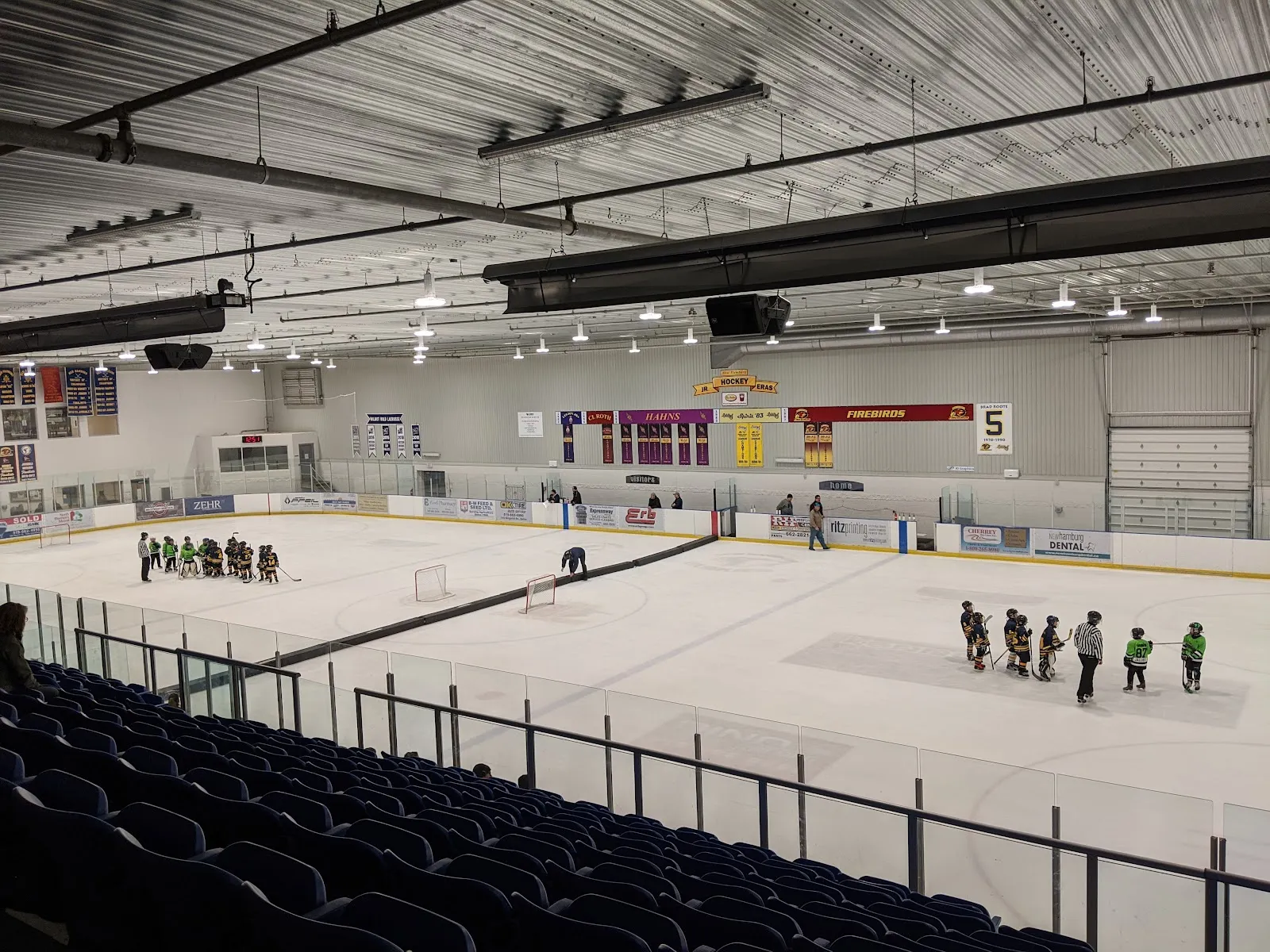 One of the two ice pads from the blue stands during a youth practice, with banners on the far wall. — Wilmot Recreation Complex (Baden)