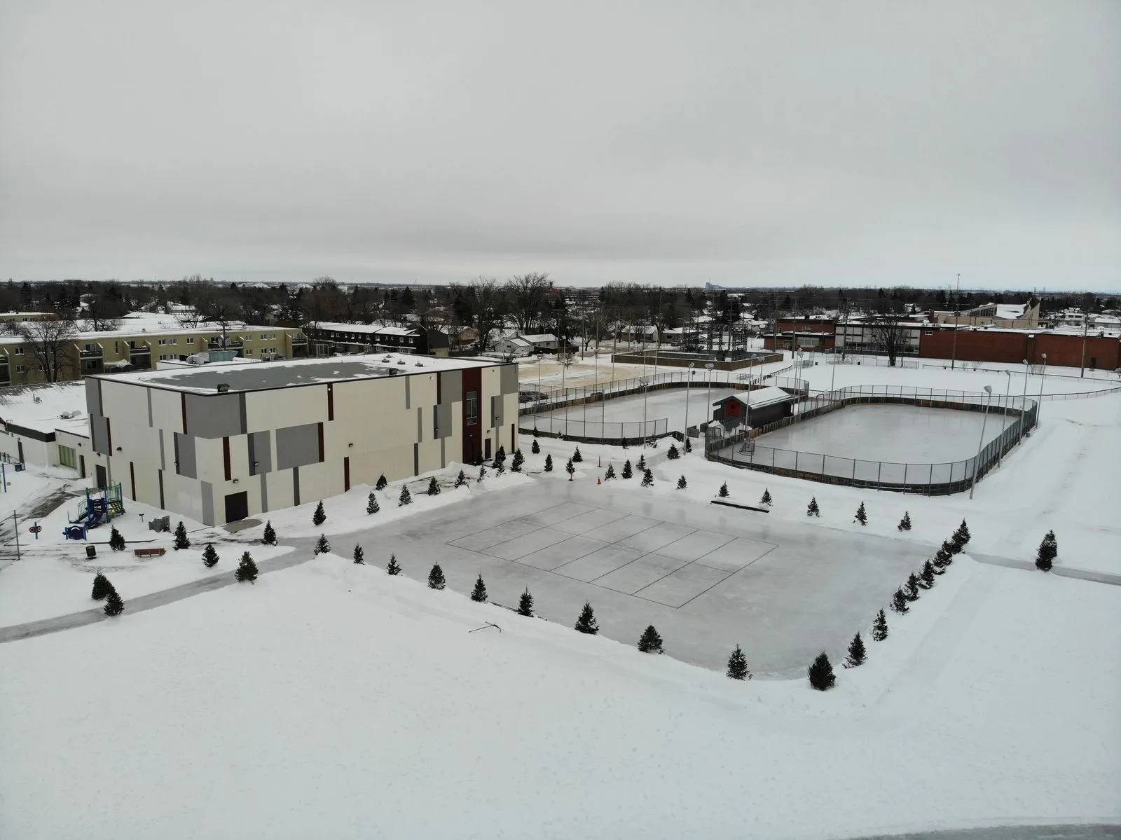 Winakwa Community Centre seen from above, with its outdoor rinks and field beside the building in winter — Winakwa Community Centre Outdoor Rinks