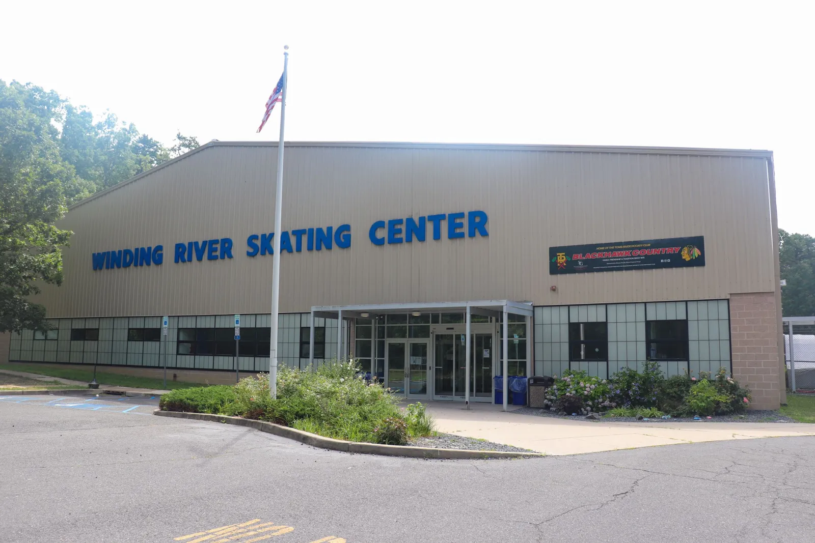 The tan metal-clad building with WINDING RIVER SKATING CENTER in blue letters, the glass entrance under a flat canopy and a Blackhawk Country banner on the wall. — Winding River Skating Center