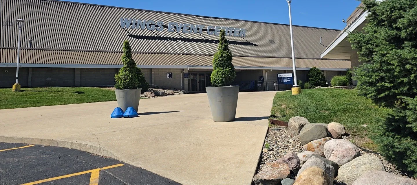 The Wings Event Center in Kalamazoo, its name in large letters along the long ribbed roof above the main entrance walk — Wings Event Center