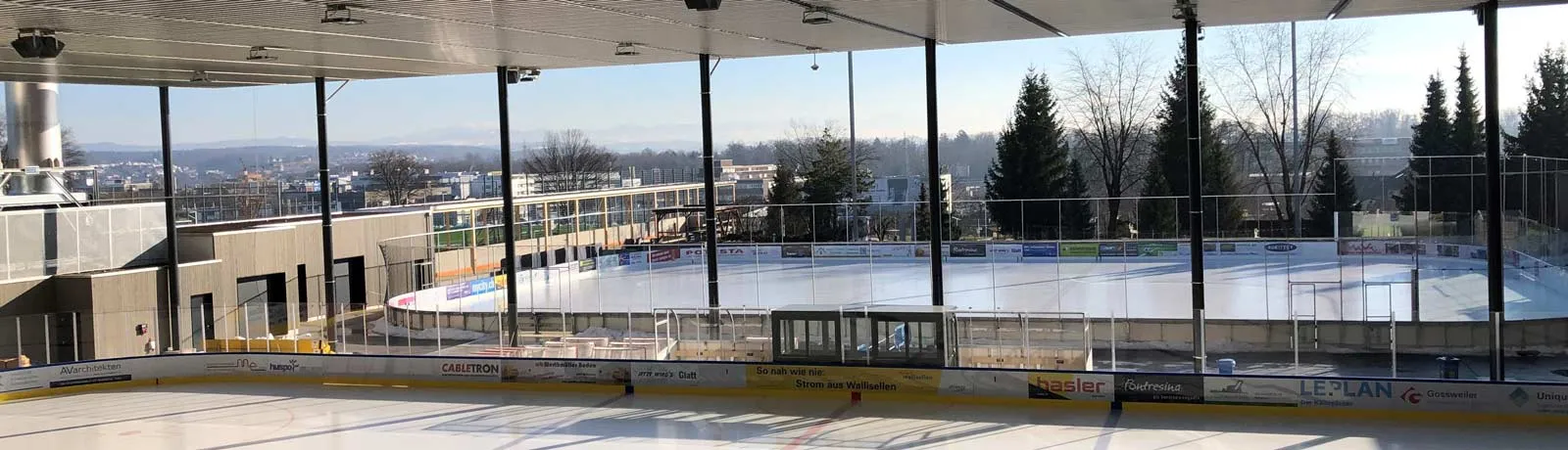 The ice surface of the Winter World in Wallisellen seen from the rink side, looking out over the hall's glazed front — Winter World Wallisellen