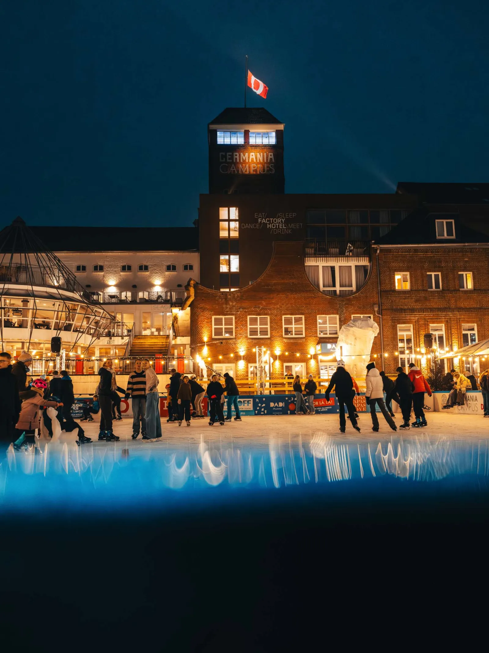 The tower of the Germania Campus above the lit-up Winterzeit rink. — Winterzeit Germania Campus