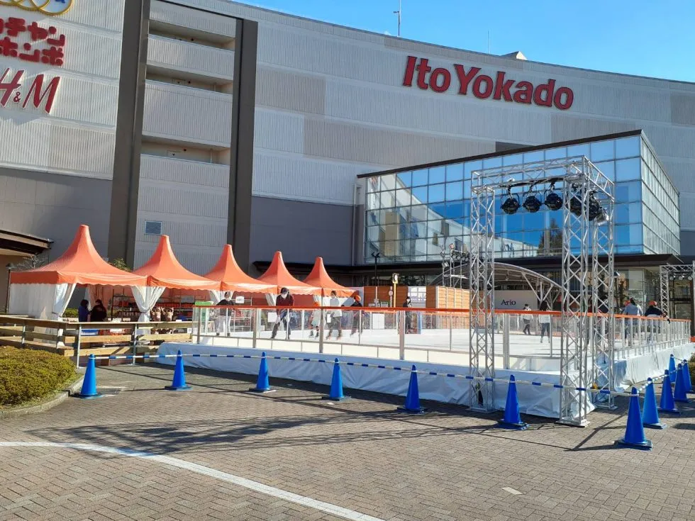 The Ario Kameari mall front with the white rink platform and orange ticket tents on the plaza. — Wonder Rink Ario Kameari