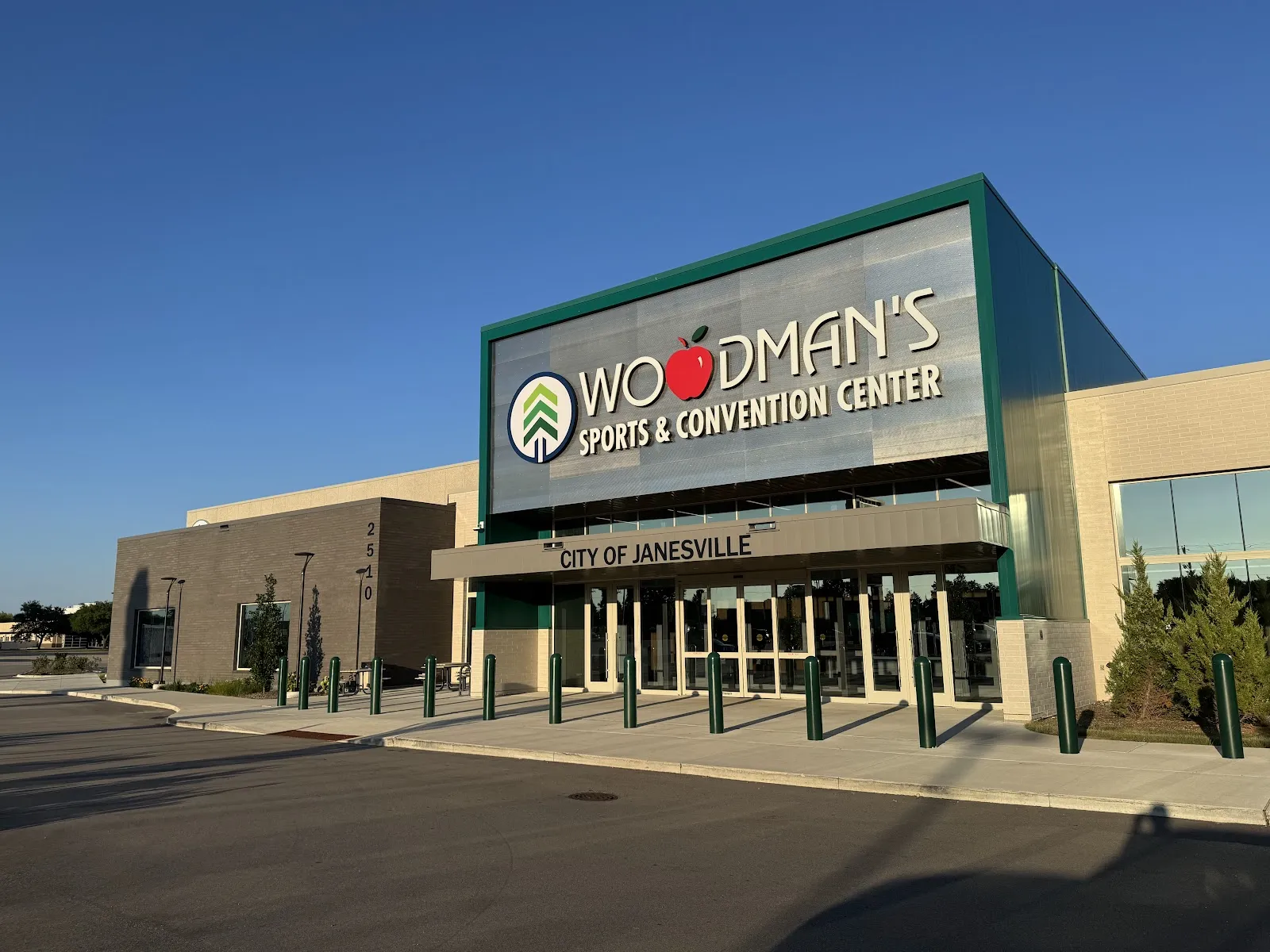 The entrance of Woodman's Sports and Convention Center in Janesville, with its name on the green and grey panel above the glass doors — Woodman's Sports and Convention Center