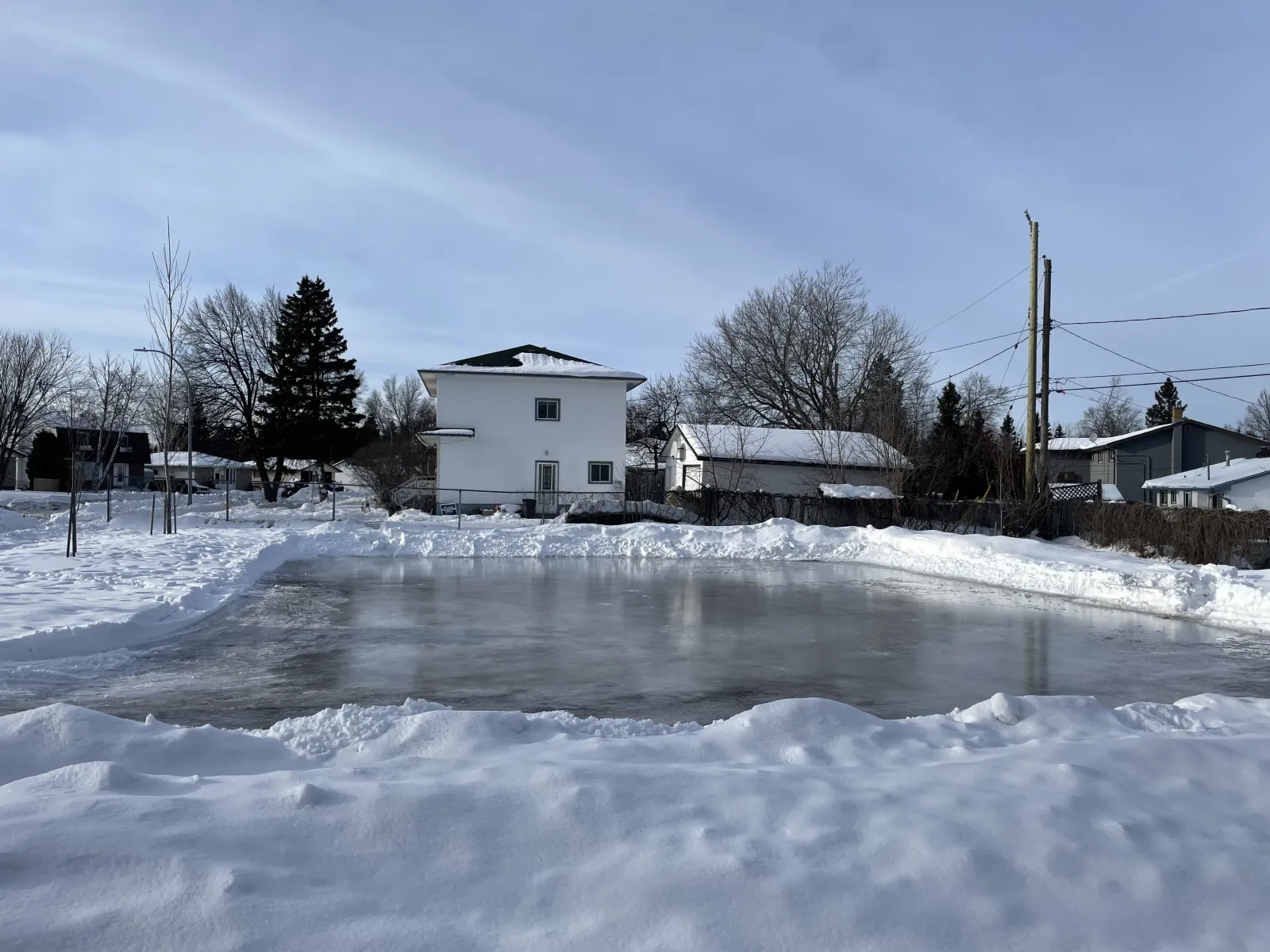 El estanque de patinaje de Woodside Parkette con casas más allá — Woodside Parkette Skating Pond