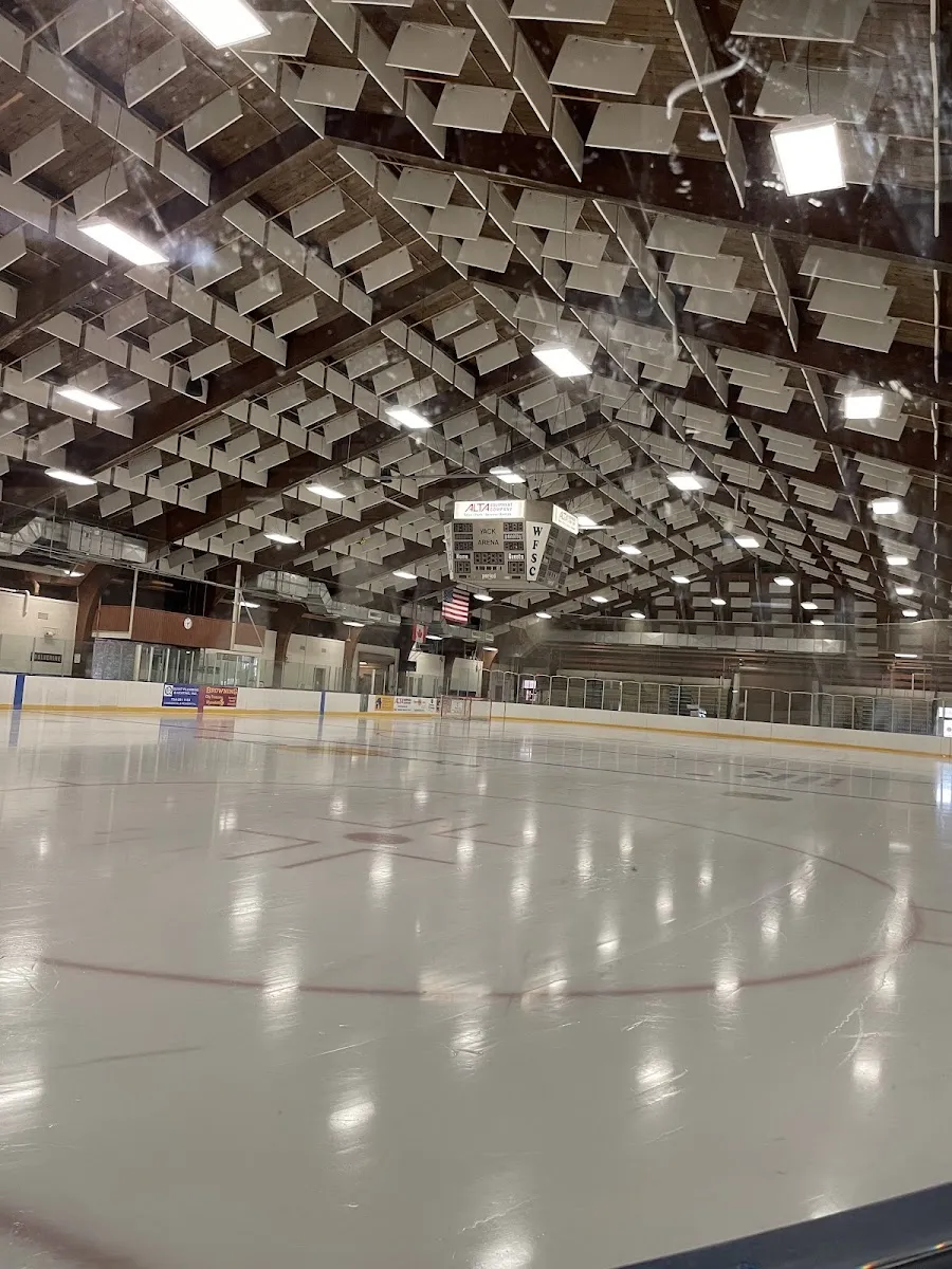 El hielo vacío de Yack Arena bajo su largo techo de vigas de madera e hileras de luces. — Yack Arena