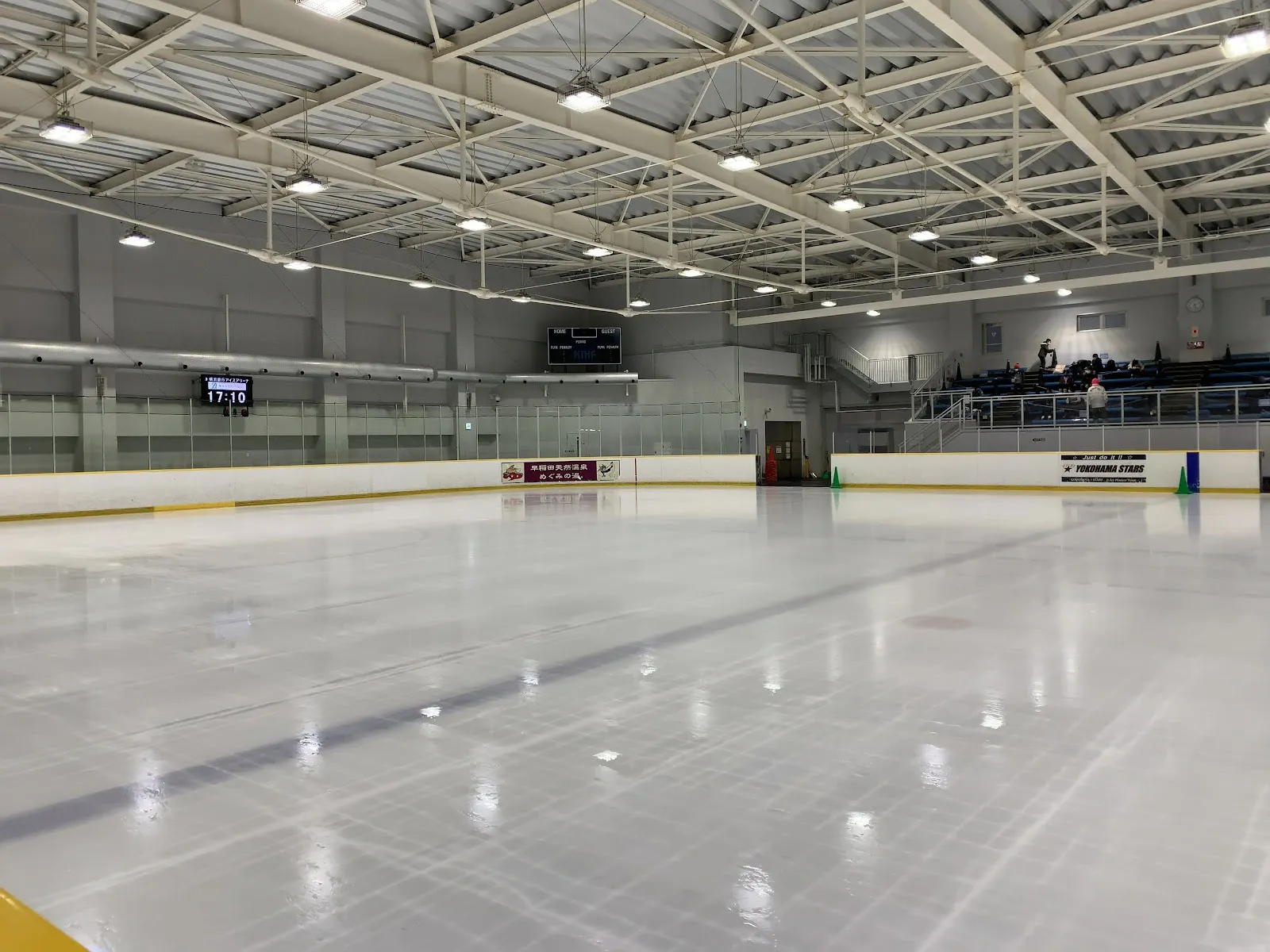 The empty main rink of the Yokohama Bank Ice Arena with the stands and score clock at the far end — Yokohama Bank Ice Arena