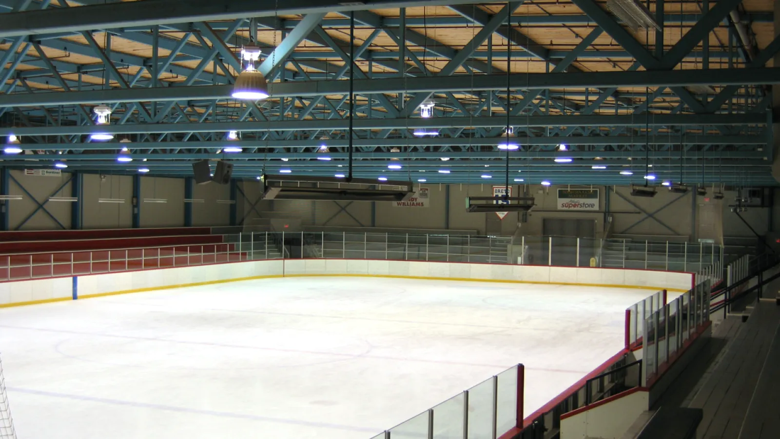 La pista de hielo dentro del York Arena bajo las cerchas de acero del techo, con las vallas y las gradas a un lado. — York Arena