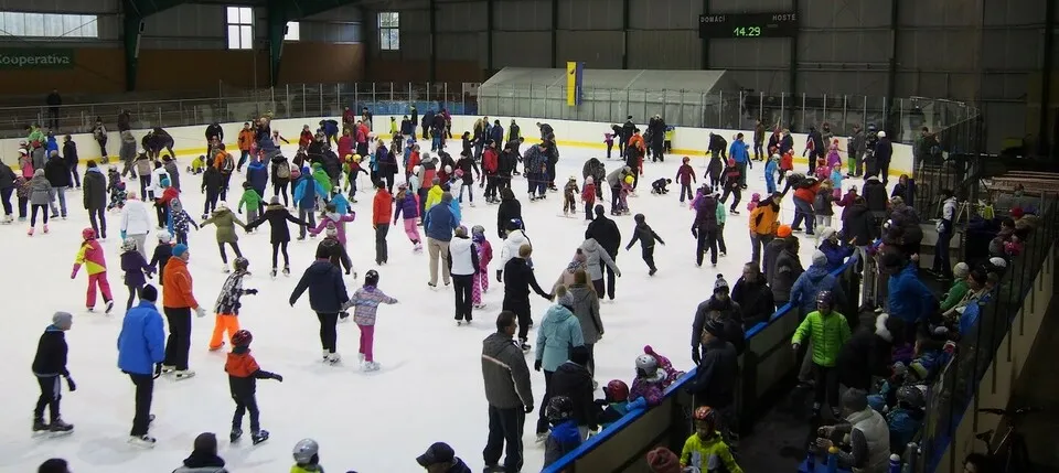 A public skating session on the ice of the Zimní stadion in Černošice, with skaters filling the sheet under the roof and the hockey boards around it — Zimní stadion Černošice