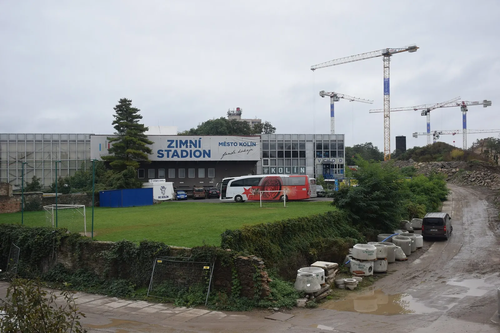 The Kolín winter stadium building with its 'Zimní stadion, Město Kolín' sign and the entrance, seen from the old town side with a team bus parked in front. — Zimní stadion Kolín
