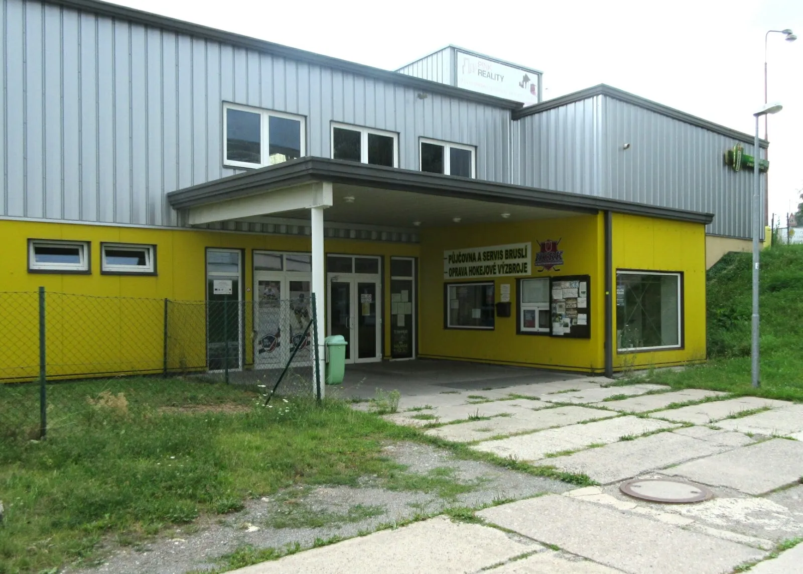 Entrance of the winter stadium in Rychnov nad Kněžnou, a yellow and grey hall building with the ticket window and notice boards — Zimní stadion Rychnov nad Kněžnou