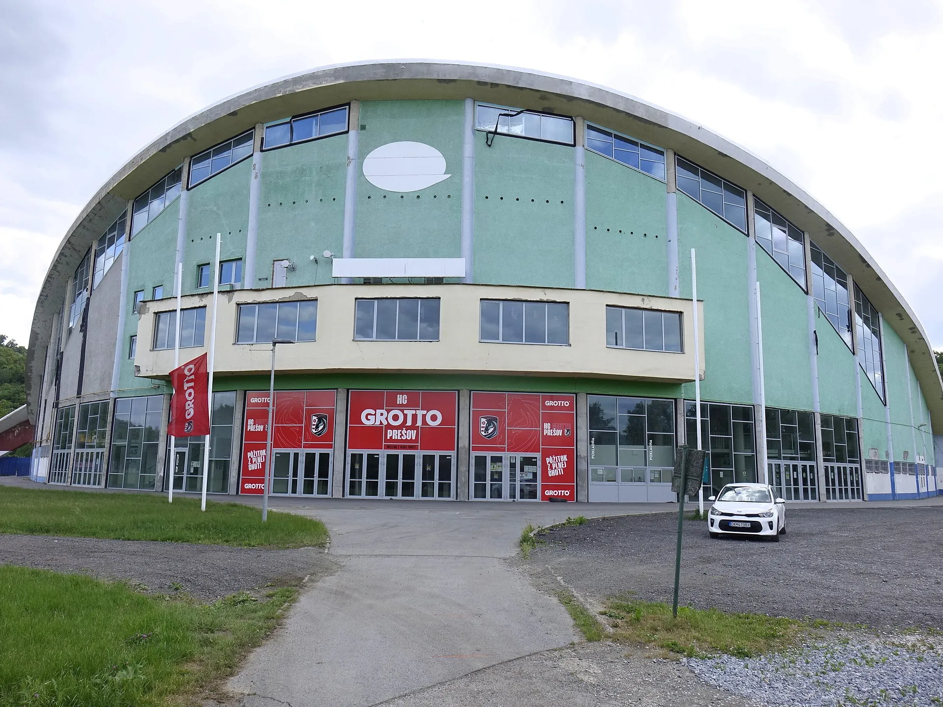 The curved-roof front of the Zimný štadión in Prešov, with the red entrance doors and the arena's name board — Zimný štadión Prešov