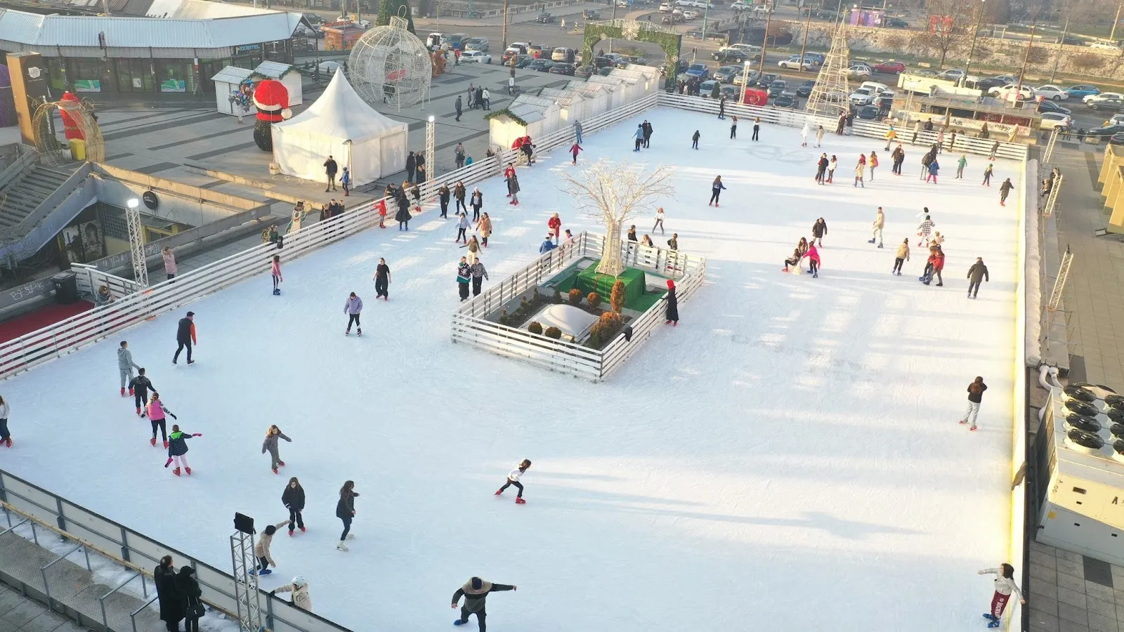 Javno klizanje na ledu klizališta Zimska čarolija u Skenderiji u Sarajevu, s klizačima na cijeloj površini i tribinama arene iza njih. — Zimska čarolija ice rink (Centar Skenderija)